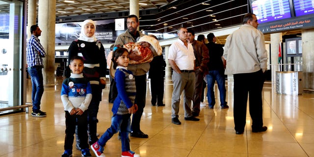 Syrian refugee Ahmad al-Abboud, center, waits with his family at the International Airport of Amman.