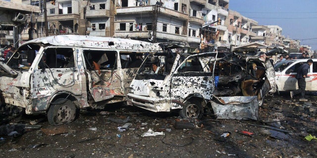 Syrian citizens gather at the scene where two blasts exploded in the pro-government neighborhood of Zahraa, in Homs province, Syria.