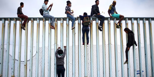Members of a caravan of migrants from Central America climb up the border fence between Mexico and the U.S., as a part of a demonstration prior to preparations for an asylum request in the U.S., in Tijuana, Mexico April 29, 2018.