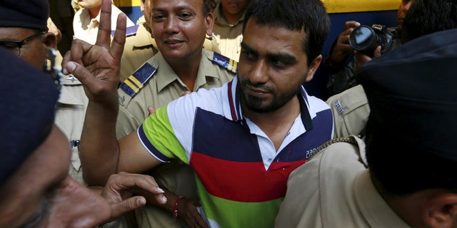 One of the 12 men, convicted of planning several blasts on crowded commuter trains in the financial capital of Mumbai in 2006, gestures as he is escorted by police to a court in Mumbai, India, September 30, 2015.
