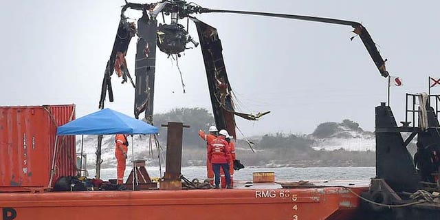 March 13, 2015: Crews lower a piece of a Black Hawk helicopter onto a barge in the Santa Rosa Sound near Pritchard Point in Navarre, Fla. (AP/Northwest Florida Daily News, Nick Tomecek)