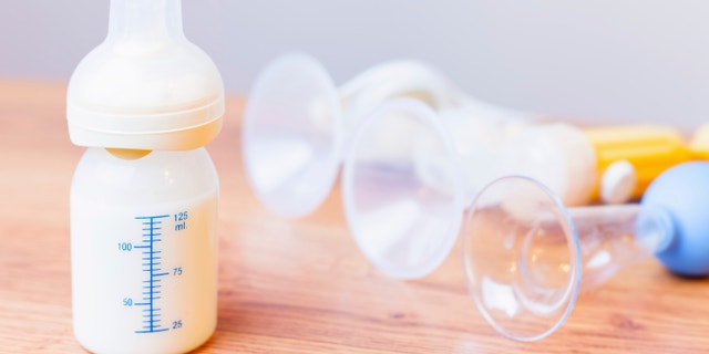 Baby bottle with milk and a measuring scale, manual breast pump, mothers breast milk is the most healthy food for newborn baby. Objects standing in a row. Selective focus