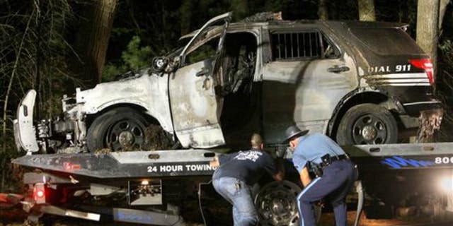 Sept. 2, 2015: A police officer assists as a cruiser that was shot at is removed from Forest Road in Millis, Mass.