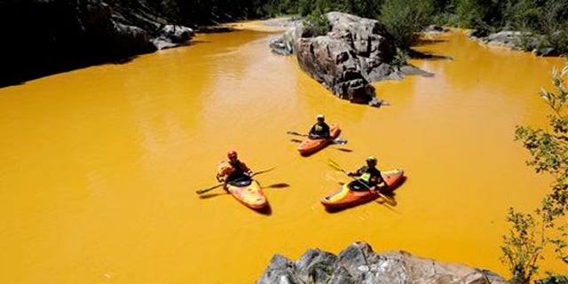 FILE - In this Aug. 6, 2015 file photo, people kayak in the Animas River near Durango, Colo., in water colored from a mine waste spill.  The federal government and Colorado have made little progress in remedying damages from the 2015 release of millions of gallons of wastewater from a southern Colorado mine, New Mexico's top prosecutor charged in a pair of scathing letters sent to officials on Friday, May 20, 2016.(Jerry McBride/The Durango Herald via AP, File) MANDATORY CREDIT
