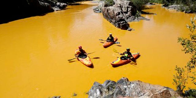 FILE - In this Aug. 6, 2015 file photo, people kayak in the Animas River near Durango, Colo., in water colored from a mine waste spill. The federal government and Colorado have made little progress in remedying damages from the 2015 release of millions of gallons of wastewater from a southern Colorado mine, New Mexico's top prosecutor charged in a pair of scathing letters sent to officials on Friday, May 20, 2016.(Jerry McBride/The Durango Herald via AP, File) MANDATORY CREDIT