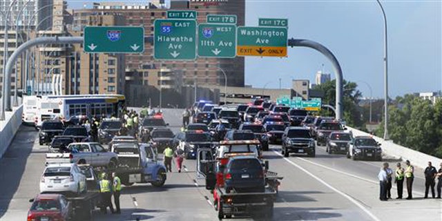 State troopers and police clear the Interstate 35W freeway where protesters blocked the highway leading into Minneapolis over the Mississippi River bridge during rush hour Wednesday, July 13, 2016.