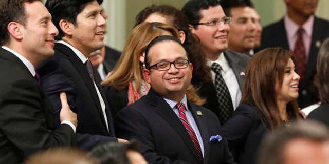 FILE - In this Sept. 12, 2013 file photo, Assemblyman Luis Alejo, D-Watsonville, center, smiles as he and other members of the Latino Caucus watch the votes being posted for Alejo's immigrant driver's license bill that was approved by the Assembly in Sacramento, Calif. California has about two dozen Latino lawmakers, yet that's just half their proportion of the state' population. Minorities remain significantly underrepresented in most state Legislatures and Congress despite comprising a growing share of the U.S. population, according to an analysis of demographic data by the Associated Press. (AP Photo/Rich Pedroncelli, File)