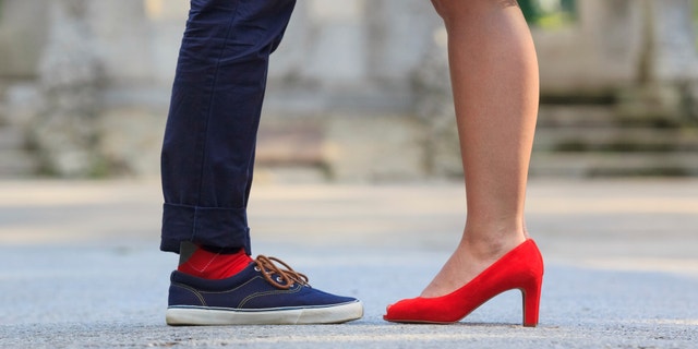 The lower legs of a woman and a man standing opposite each other - red is the unifying color