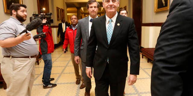 FILE -- April 1, 2016: Republican Gov. Phil Bryant, right, walks past reporters on his way to a meeting of a youth jobs program board, at the Capitol in Jackson, Miss.