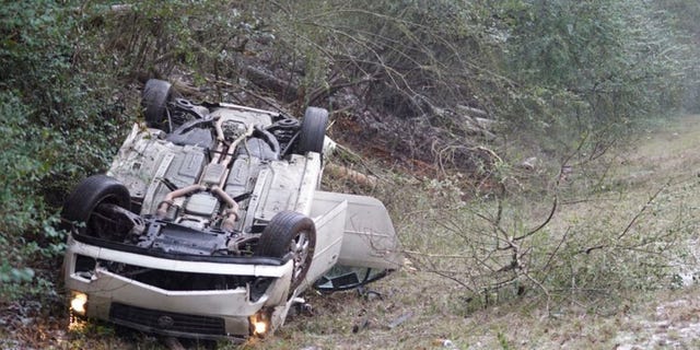 In this image, a car sits upside down on the side of the road after the vehicle flipped in front of the Mississippi State team bus in Mississippi, as the players were heading to LSU for an NCAA college basketball game.