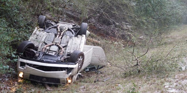 In this image, a car sits upside down on the side of the road after the vehicle flipped in front of the Mississippi State team bus in Mississippi, as the players were heading to LSU for an NCAA college basketball game.