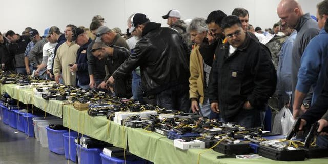 Dec. 22, 2012: People look over a table of handguns for sale at a gun show in Kansas City, Missouri.