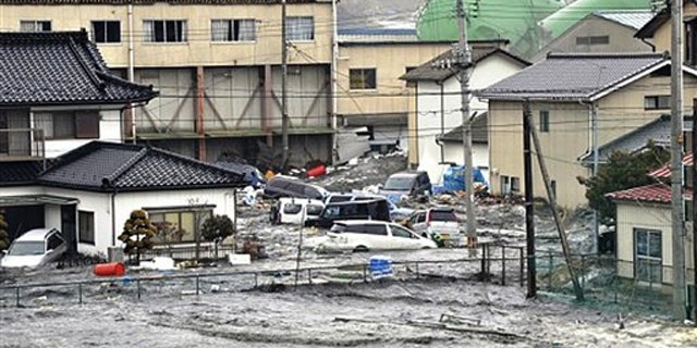 An earthquake-triggered tsunami washes away a warehouse and vehicles in Kesennuma, Miyagi in Japan March 11.