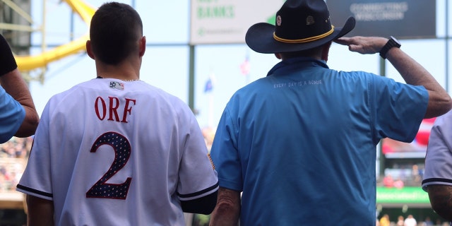 A veteran stands next to Brewers player Nate Orf.