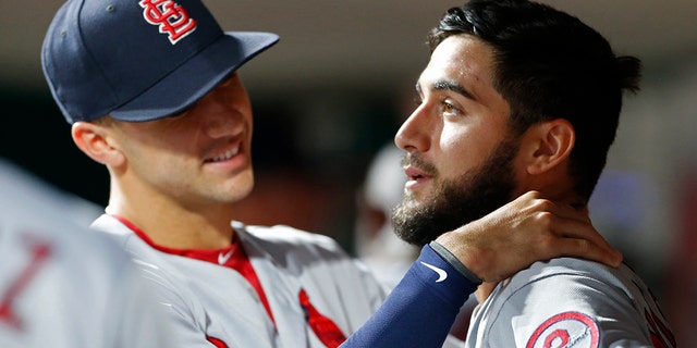 St. Louis Cardinals starting pitcher Daniel Poncedeleon, right, gets a hug in the dugout by Jack Flaherty, left, following seven no-hit innings against the Cincinnati Reds in a baseball game.