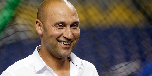 Miami Marlins CEO Derek Jeter smiles as he watches batting practice before a baseball game against the Los Angeles Dodgers.