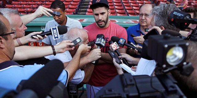 Boston Red Sox's J.D. Martinez is surrounded by reporters while discussing social media postings he made prior to joining the team prior to a baseball game at Fenway Park.