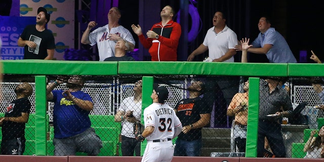 Miami Marlins left fielder Derek Dietrich (32) and fans look on as a ball hit by New York Mets' Asdrubal Cabrera goes over the wall for a home run during the fourth inning.