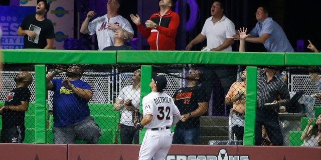 Miami Marlins left fielder Derek Dietrich (32) and fans look on as a ball hit by New York Mets' Asdrubal Cabrera goes over the wall for a home run during the fourth inning.