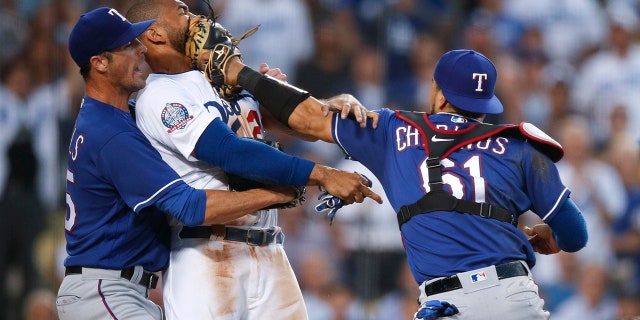 Texas Rangers starting pitcher Cole Hamels, left, restrains Los Angeles Dodgers' Matt Kemp as Kemp scuffles with Rangers catcher Robinson Chirinos during the third inning of a baseball game.