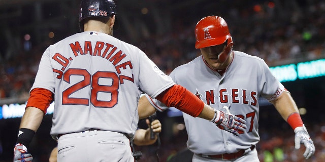 Los Angeles Angels outfielder Mike Trout, right, is welcomed at the dugout by All-Star Game teammate J.D. Martinez after belting a solo home run during the third inning.