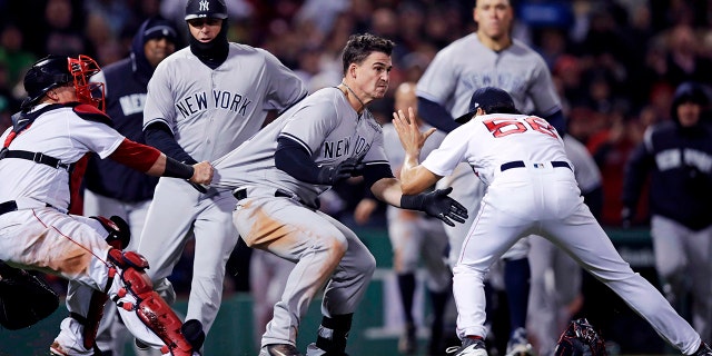 New York Yankees' Tyler Austin, center, rushes Boston Red Sox relief pitcher Joe Kelly, right, after being hit by a pitch during the seventh inning of a baseball game at Fenway Park in Boston.
