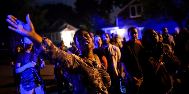 Minneapolis NAACP President Leslie Badue called for the attention of the crowd gathered before leading a prayer in response to an officer-involved shooting in Minneapolis.