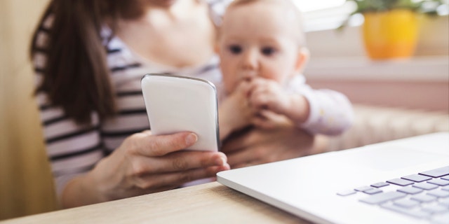 Young mother in home office with computer and her daugher