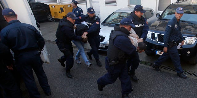 Oct. 16, 2016: Montenegrin police officers escort people suspected of planning armed attacks after the parliamentary vote in Podgorica, Montenegro.