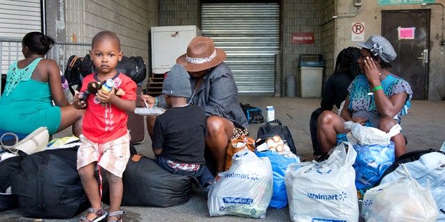 A group of Haitian asylum seekers sit with shopping bags outside the Olympic Stadium, which was temporary used as a shelter for asylum seekers, in Montreal, Quebec, Canada August 2, 2017.