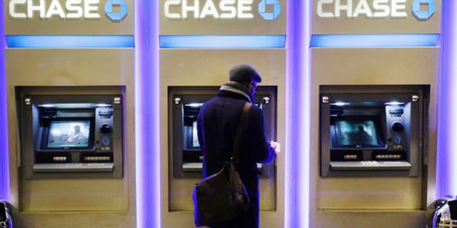 FILE - In this Wednesday, Jan. 14, 2015, file photo, a customer uses an ATM at a branch of Chase Bank, in New York. Fewer Americans are without access to a checking or savings account, according to a survey released Thursday, Oct. 20, 2016, by federal regulators, a sign that the improving economy is helping lift the nation's poorest households. (AP Photo/Mark Lennihan, File)