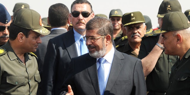Oct. 10, 2012: In this file photo released by the Egyptian Presidency, then Egyptian President Mohammed Morsi, center, speaks with Minister of Defense, Lt. Gen. Abdel-Fattah el-Sissi, left, at a military base in Ismailia, Egypt. An Egyptian court has set Nov. 4, 2013, as the start date for the trial of ousted President Mohammed Morsi on charges of incitement to murder for the killings of opponents who were rallying outside his palace while he was in office.