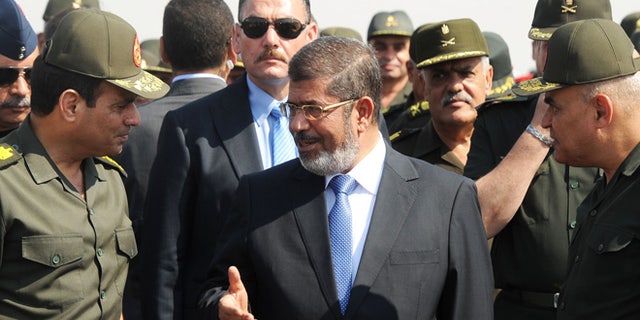 Oct. 10, 2012: In this file photo released by the Egyptian Presidency, then Egyptian President Mohammed Morsi, center, speaks with Minister of Defense, Lt. Gen. Abdel-Fattah el-Sissi, left, at a military base in Ismailia, Egypt. An Egyptian court has set Nov. 4, 2013, as the start date for the trial of ousted President Mohammed Morsi on charges of incitement to murder for the killings of opponents who were rallying outside his palace while he was in office.
