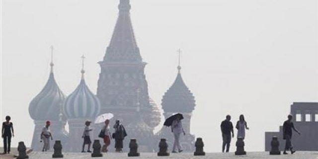People walk along Red Square, with St. Basil's Cathedral seen through heavy smog caused by peat fires in out-of-city forests, in Moscow, July 26, 2010.