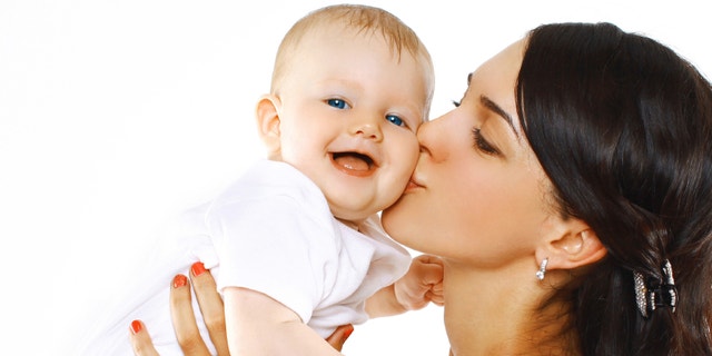 Happy family mother kissing baby