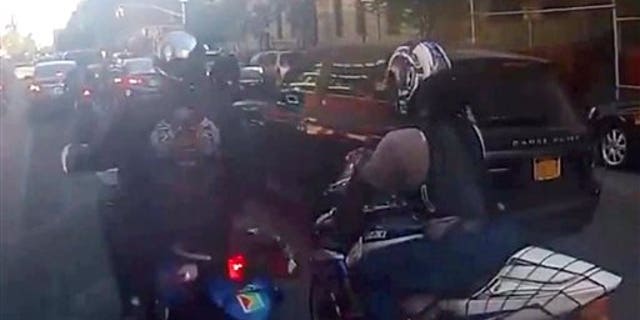 In this frame grab from video, motorcyclists ride alongside a sport utility vehicle, Sunday, Sept. 29, 2013, in New York.