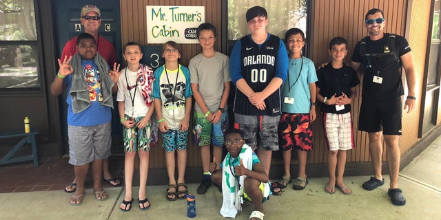 A group of campers and counselors staying in Mr. Turner's honorary cabin pose for a picture, thanking the WWII veteran.