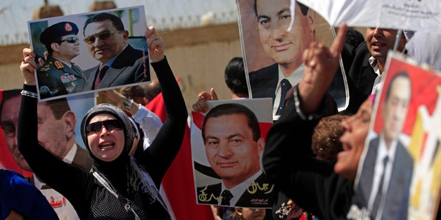 Aug. 25, 2013: Supporters of former Egyptian President Hosni Mubarak, hold posters of him as they protest outside the Cairo Police Academy turned court, Cairo, Egypt, Sunday. Mubarak, under house arrest after being released from detention last week, is standing retrial in charges of complicity in the killings of protesters during 2011 Egyptian uprising.