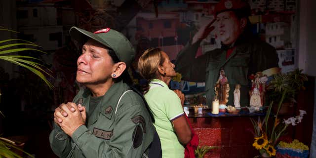Marisol Perez, Venezuelan Army specialist, cries while visiting a chapel near Venezuela's late President Hugo Chavez's mausoleum in Caracas, Venezuela, Wednesday, March 5, 2014. Wednesday's anniversary of Chavez's death follows weeks of sometimes violent protests that the government says have left 18 dead. To mark Chavez's passing, who died March 5, 2013 at the age of 58, President Nicolas Maduro has decreed a 10-day-long commemoration. (AP Photo/Rodrigo Abd)
