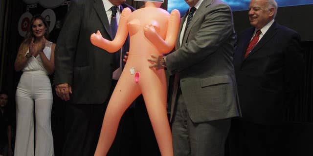 Photo provided on Dec. 14, 2016 shows Chile's Economy Minister Luis Felipe Cespedes (R), receiving a inflatable doll as a present FROM the Manufacturing Exporters Association (ASEXMA) in Santiago, Chile on Dec. 13, 2016.