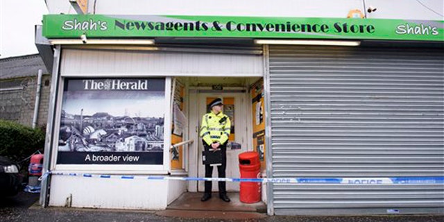 FILE: A police officer stands outside the shop where Asad Shah worked in Glasgow.