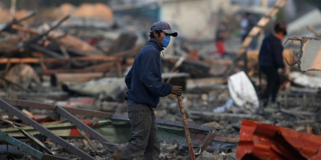 A man walks through the scorched ground of the open-air San Pablito fireworks market, in Tultepec, Mexico, Dec. 20, 2016.