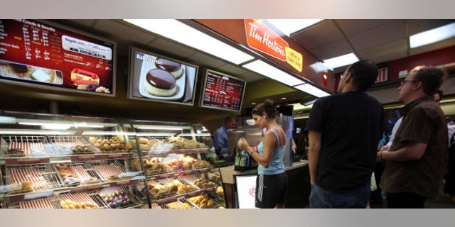 Costumers line up at the Tim Hortons coffee shop inside New York's Penn Station, Monday, July 13, 2009. Canadian doughnut and coffee chain Tim Hortons Inc. said it is opening 12 new locations in New York City, with three more planned for August. (AP Photo/Mary Altaffer)