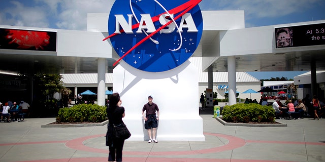 File photo: Tourists take pictures of a NASA sign at the Kennedy Space Center visitors complex in Cape Canaveral, Florida April 14, 2010. (REUTERS/Carlos Barria)