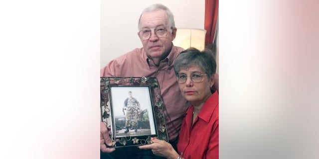 Will and Lynn Chapman holding a photo of their son, Sgt. 1st Class Nathan Ross Chapman, in 2002.