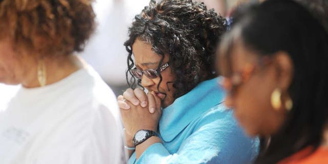 A woman is shown deep in prayer as she sits on a church pew in a house of worship. (Associated Press)