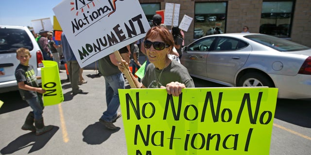 A woman holds protest signs after U.S. Interior Secretary Sally Jewell arrived on July 14, 2016, for a meeting with San Juan County Commissioners in Monticello, Utah, one of the sites that have become a key flashpoint over use of public land in the U.S. West.
