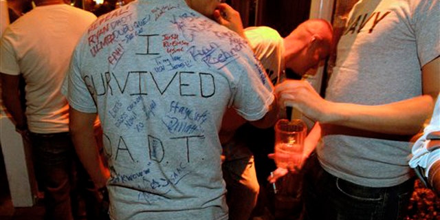 A man who is active-duty in the Navy wears a shirt being signed by others that reads 'I survived D.A.D.T.' shortly before midnight during a celebration for the end of the policy Sept. 19 in a bar in San Diego.