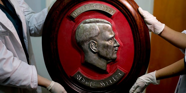 Members of the federal police show a bust relief portrait of Nazi leader Adolf Hitler at the Interpol headquarters in Buenos Aires, Argentina, Friday, June 16, 2017. In a hidden room in a house near Argentina's capital, police discovered on June 8th the biggest collection of Nazi artifacts in the country's history. Authorities say they suspect they are originals that belonged to high-ranking Nazis in Germany during World War II. (AP Photo/Natacha Pisarenko)