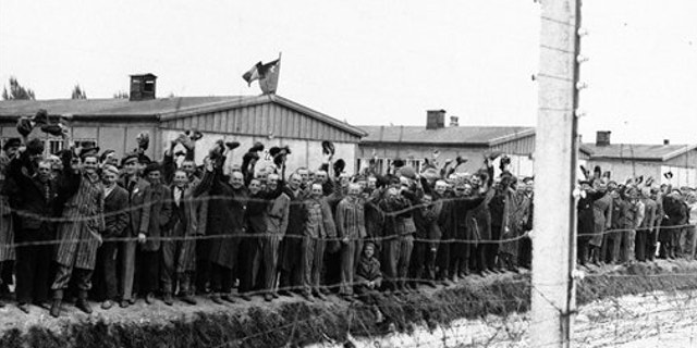 UNDATED: Prisoners at the electric fence of Dachau concentration camp cheer the Americans. German prosecutors say they are investigating a former Nazi concentration camp guard in the Berlin area on suspicion of murder after receiving a tip from the Simon Wiesenthal Center.